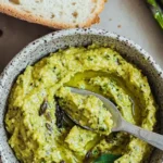 a bowl of green food with a spoon