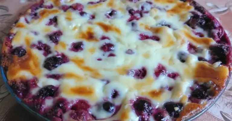 Valkosuklainen marjarahkapiiras leikattuna lusikalla mustikoita ja vadelmia